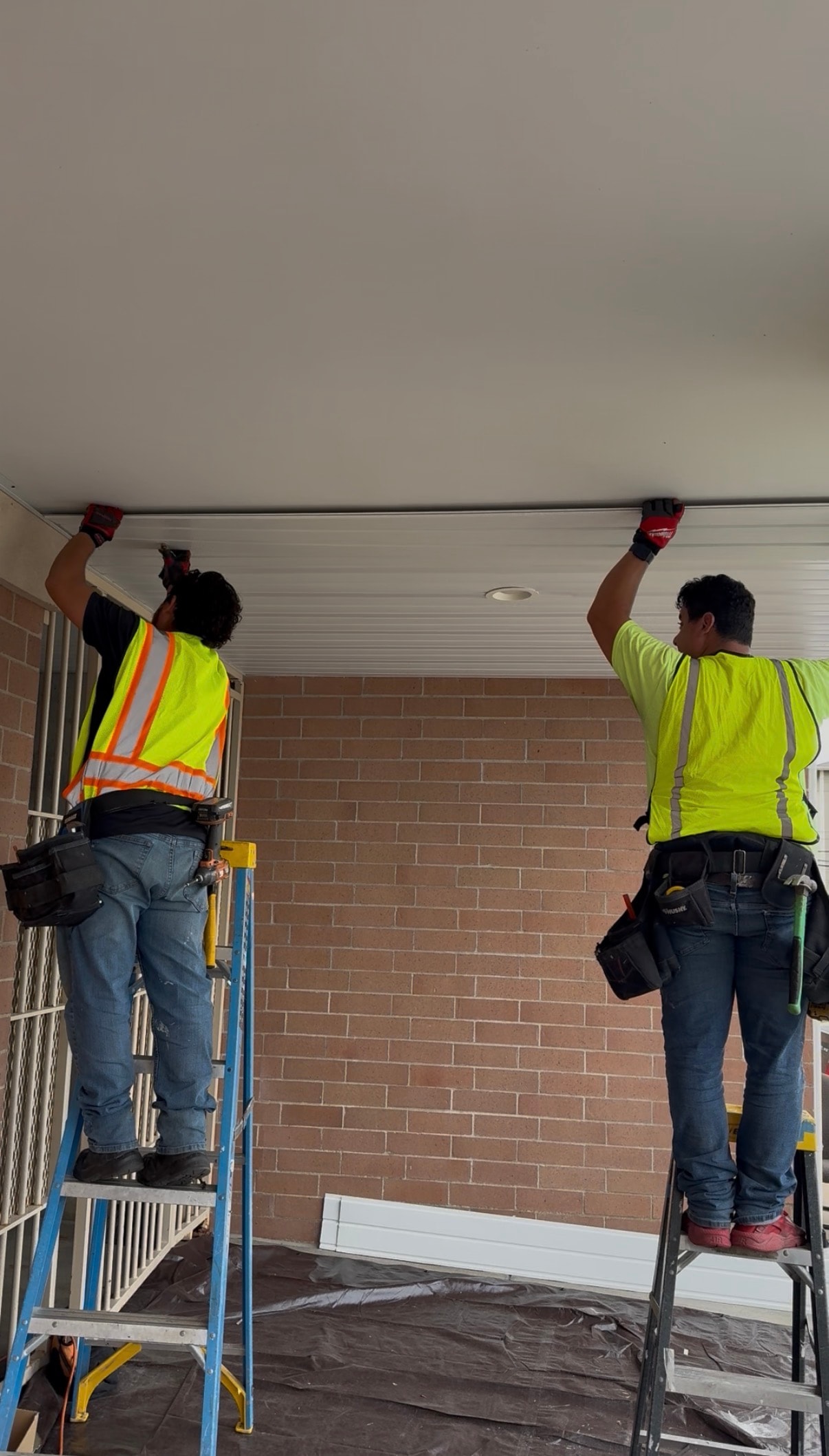 Crew installing soffit panels on brick exterior